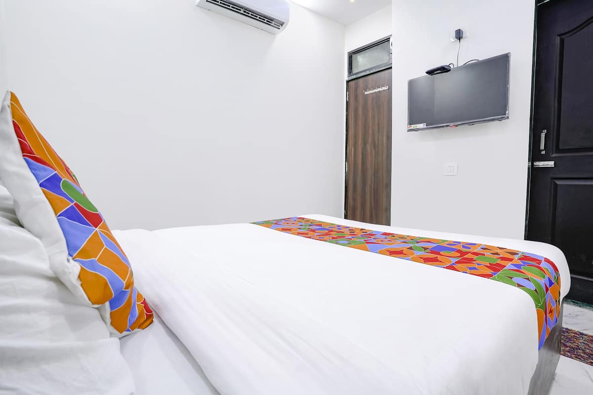 A hotel room with a bed, a TV mounted on the wall, and a door.