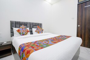 Una habitación de hotel con una cama grande, un cabecero tapizado de color gris y un armario de madera.