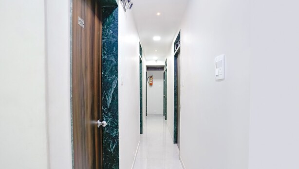 A hotel corridor with marble doors, white walls, and a tiled floor. - Fabexpress Bhau Residency (Mumbai)