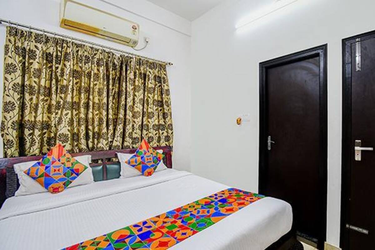 A hotel room with a bed, curtains, and two doors.