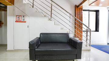 Un interior moderno con una escalera, un sofá de cuero negro y un cartel que prohíbe comer.
