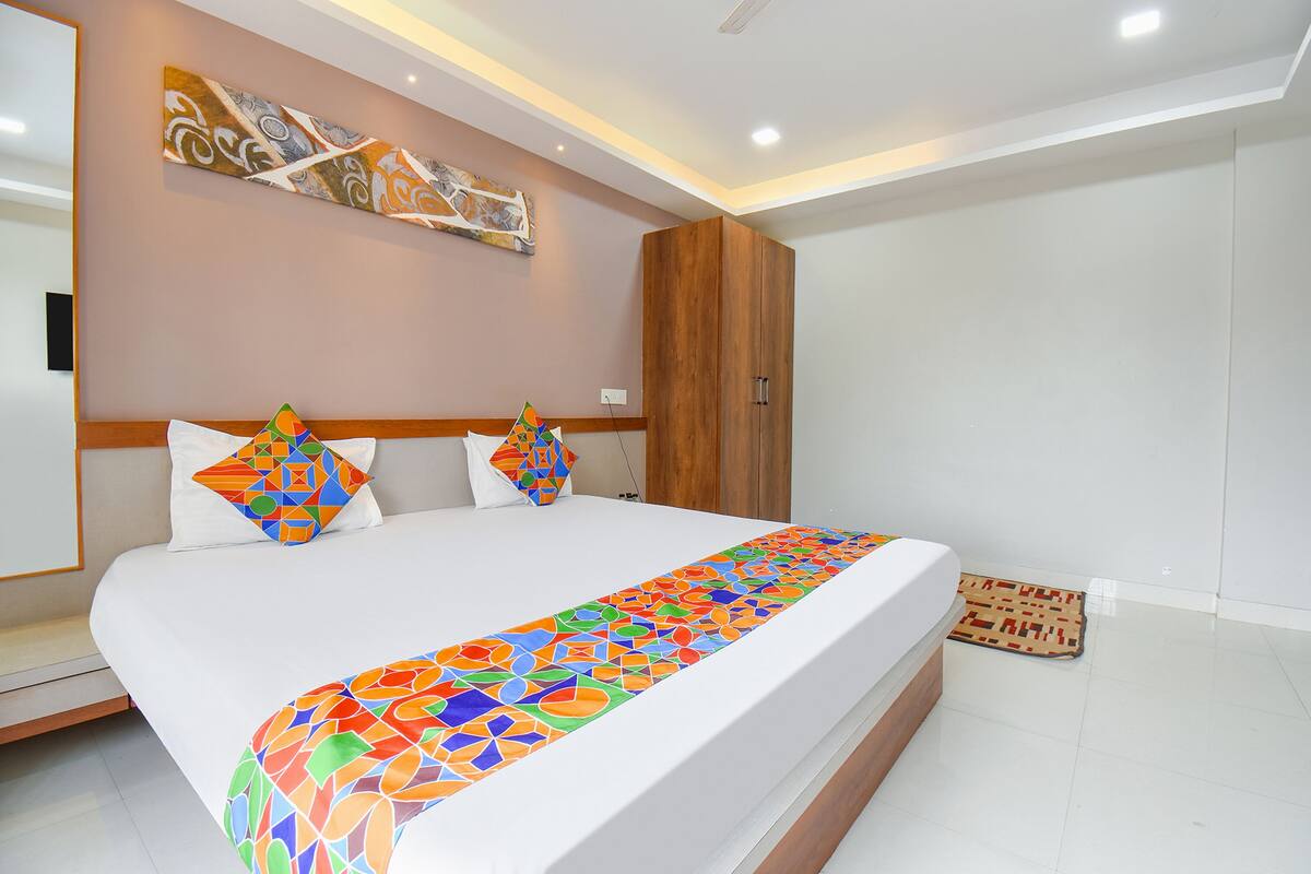 Un dormitorio moderno con una cama grande, un armario de madera y un cuadro abstracto colorido en la pared.