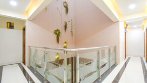 Un interior moderno con barandilla de vidrio, suelo de mármol y plantas decorativas en la pared.