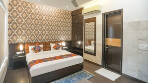 A modern hotel room with a large bed, a ceiling fan, a wardrobe, a mirror, and an air conditioning unit. - FabHotel Rivlet Residency (Gurugram)