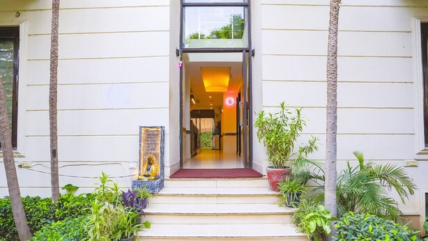 A building entrance with a red carpet, steps, and potted plants. - FabHotel Rivlet Residency (Gurugram)