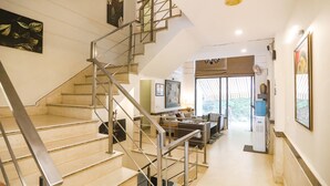 A staircase with metal railings leading to a living area with a sofa, a coffee table, and a large window. - FabHotel Rivlet Residency (Gurugram)