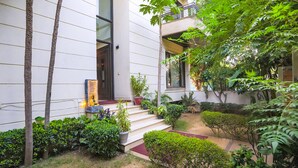A modern building with a staircase leading to a door, surrounded by lush greenery and potted plants. - FabHotel Rivlet Residency (Gurugram)