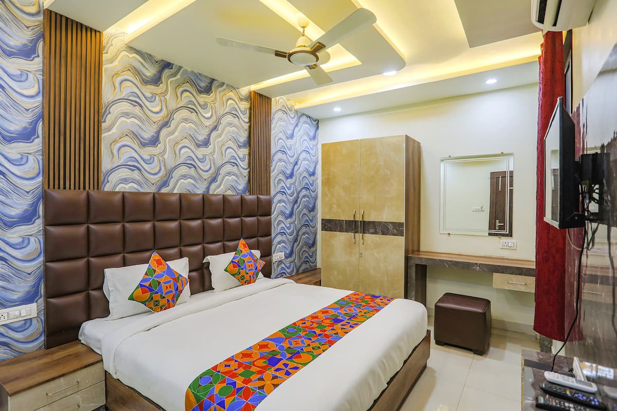 A modern hotel room with a large bed, a wardrobe, a television, and a ceiling fan.