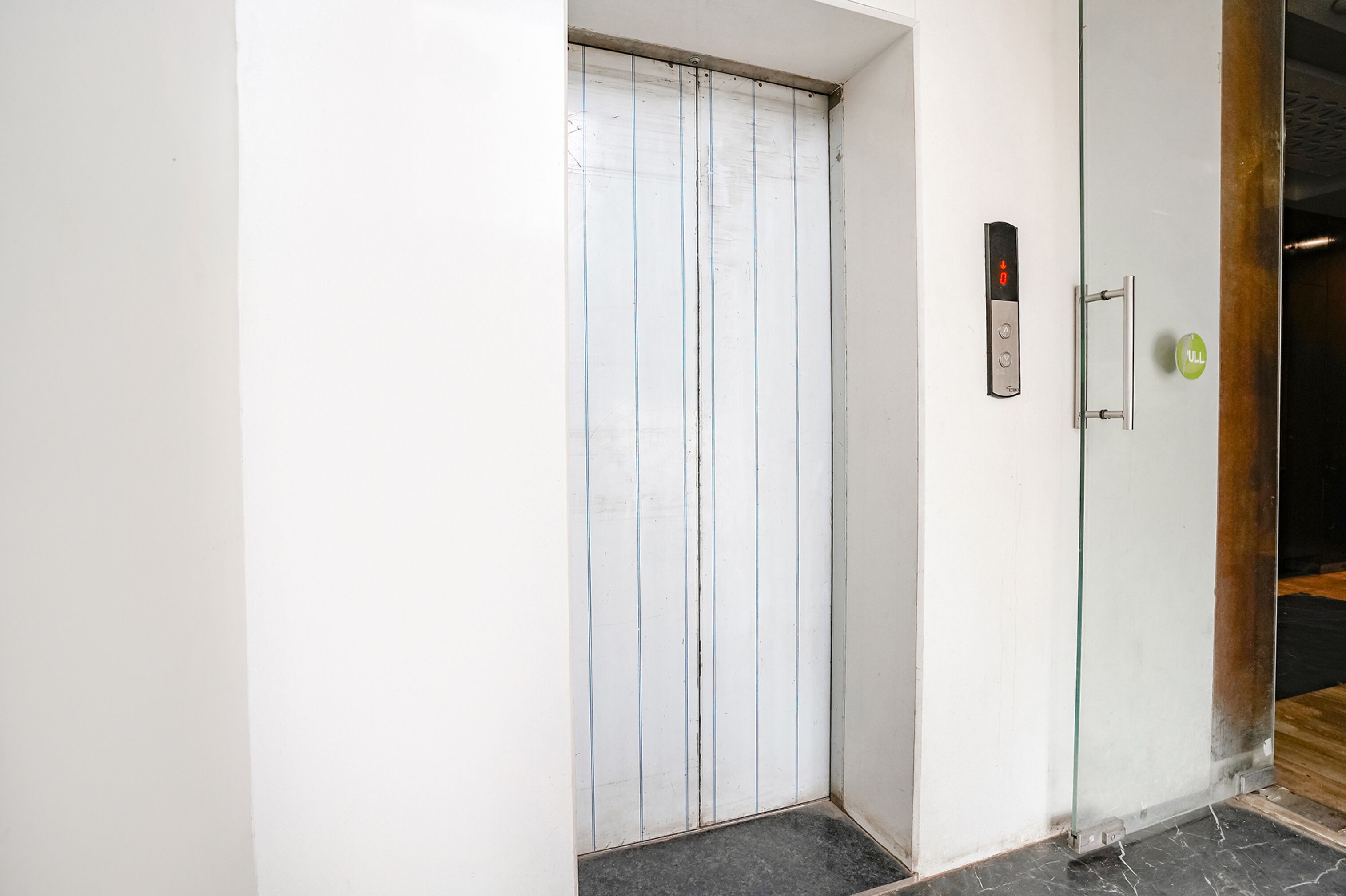 Een lift met een glazen deur en bedieningspaneel.
