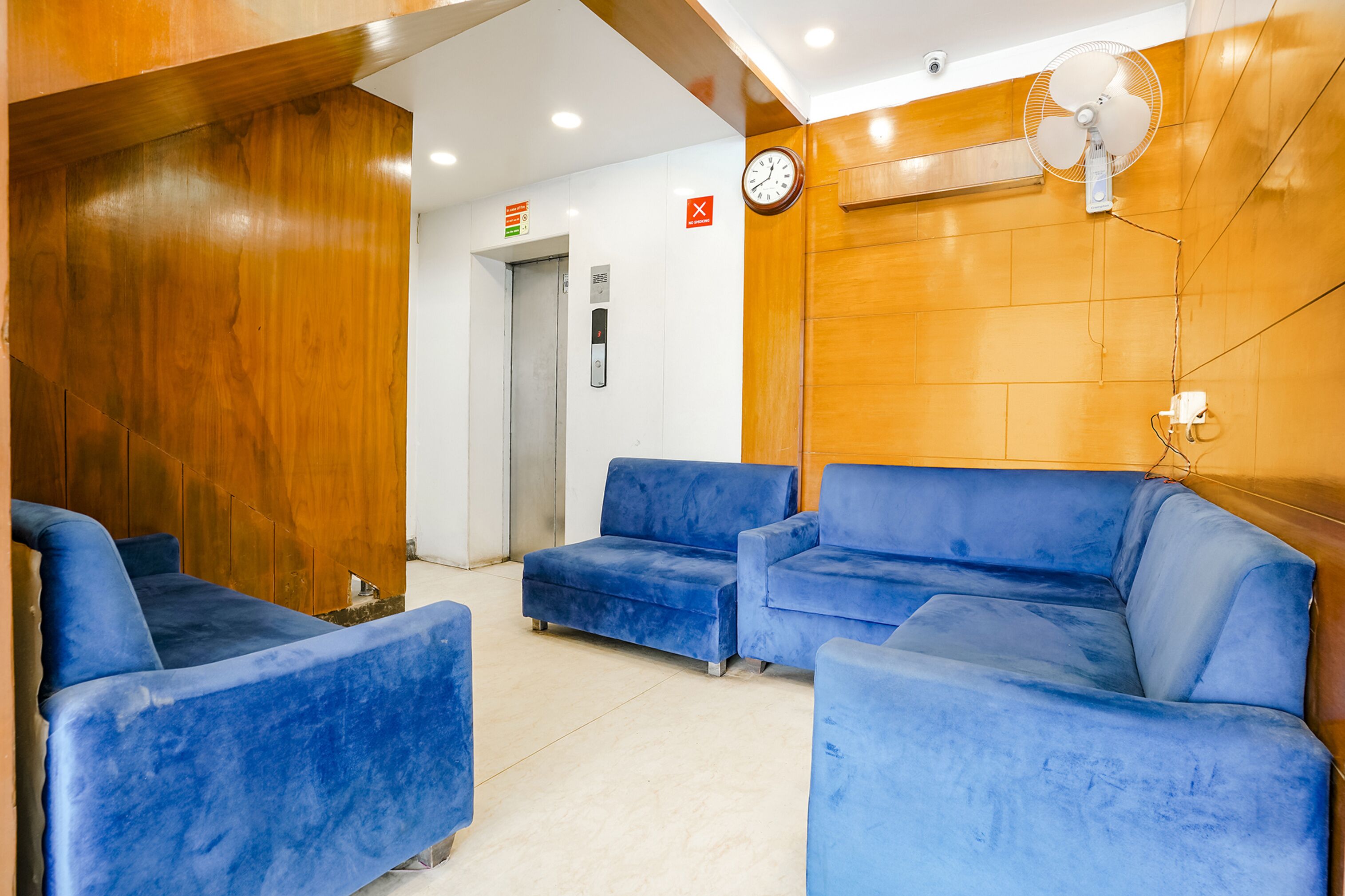 A reception area with blue sofas, a clock, and a wooden wall.