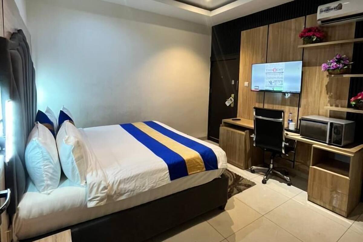 Une chambre d’hôtel moderne équipée d’un grand lit, d’un bureau, d’une chaise, d’une télévision et d’un mini-bar.