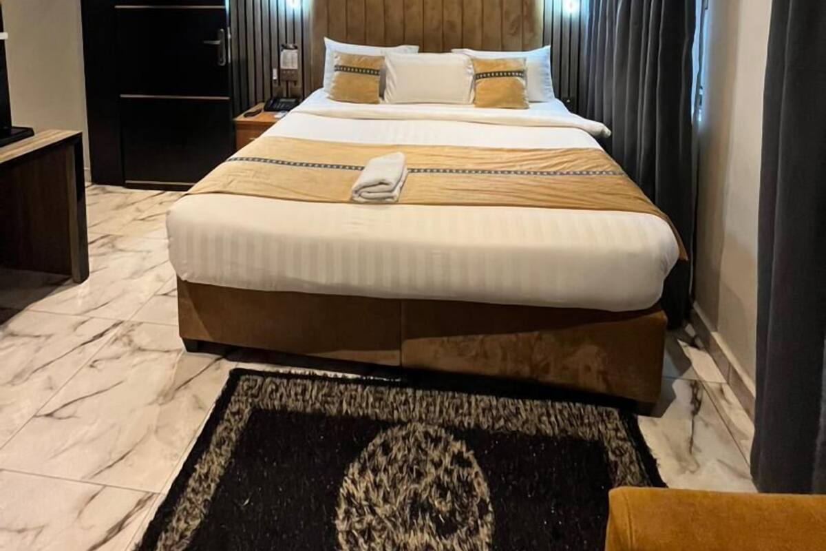 Une chambre d’hôtel moderne dotée d’un grand lit, d’un téléviseur à écran plat, d’une armoire et d’un appareil de climatisation fixé au plafond.
