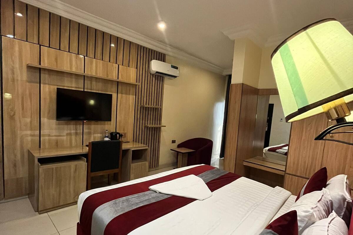 Une chambre d’hôtel avec un grand lit, un bureau avec une chaise, un téléviseur fixé au mur et un appareil de climatisation.