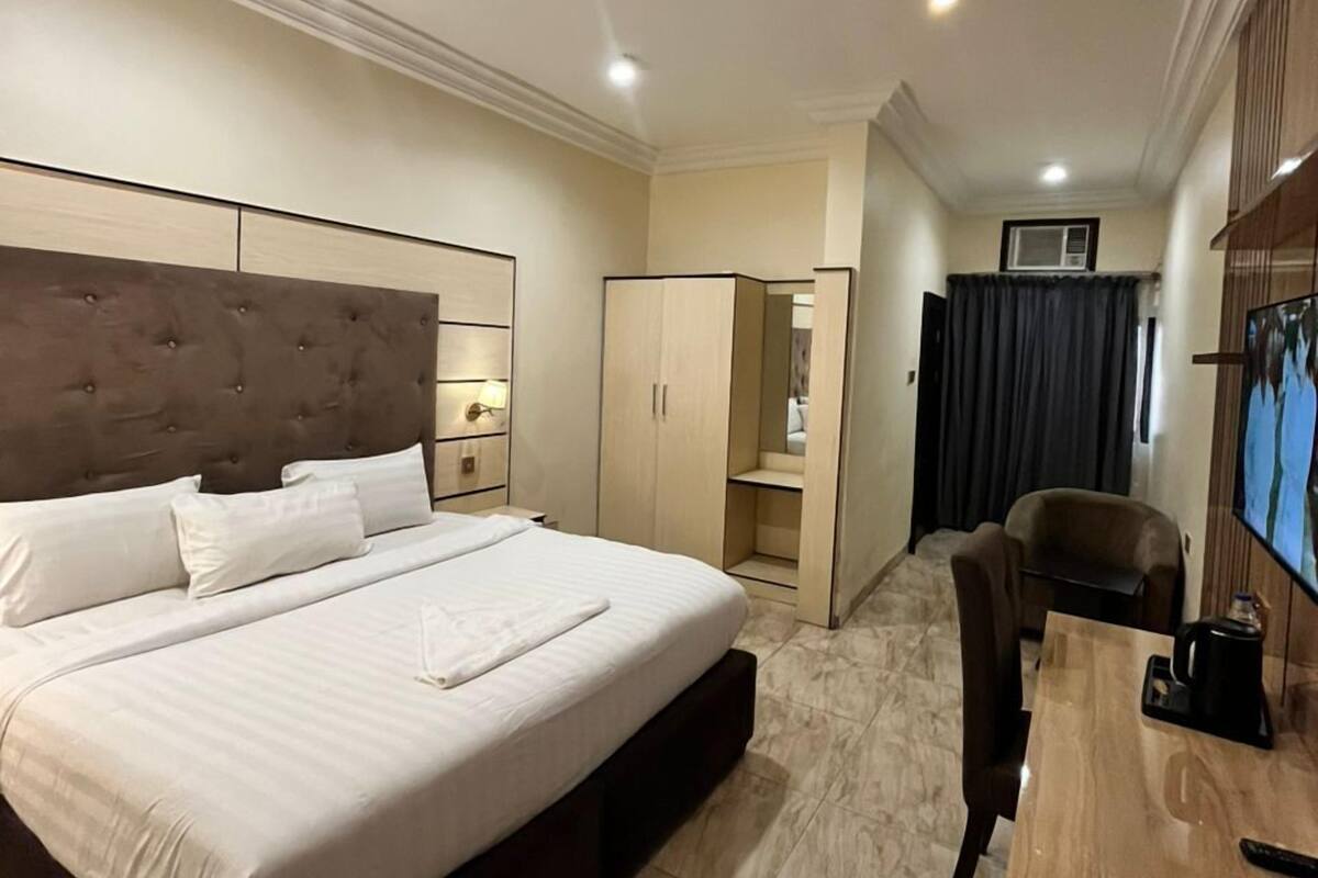 Une chambre d’hôtel avec un grand lit, un bureau, une chaise et un téléviseur.