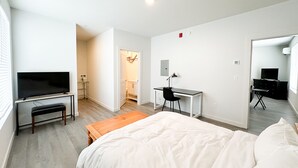 A modern bedroom with a bed, a desk, a chair, and a TV.