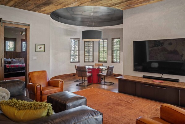 A modern living room with leather sofas, a dining table, and a flat-screen TV. - Elevated Mountain Ski Home by InvitedHome | New Remodel, Patio Views, Game Room (Mountain Village)