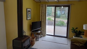 Una sala de estar con chimenea, televisor y puerta corrediza que da a un patio.