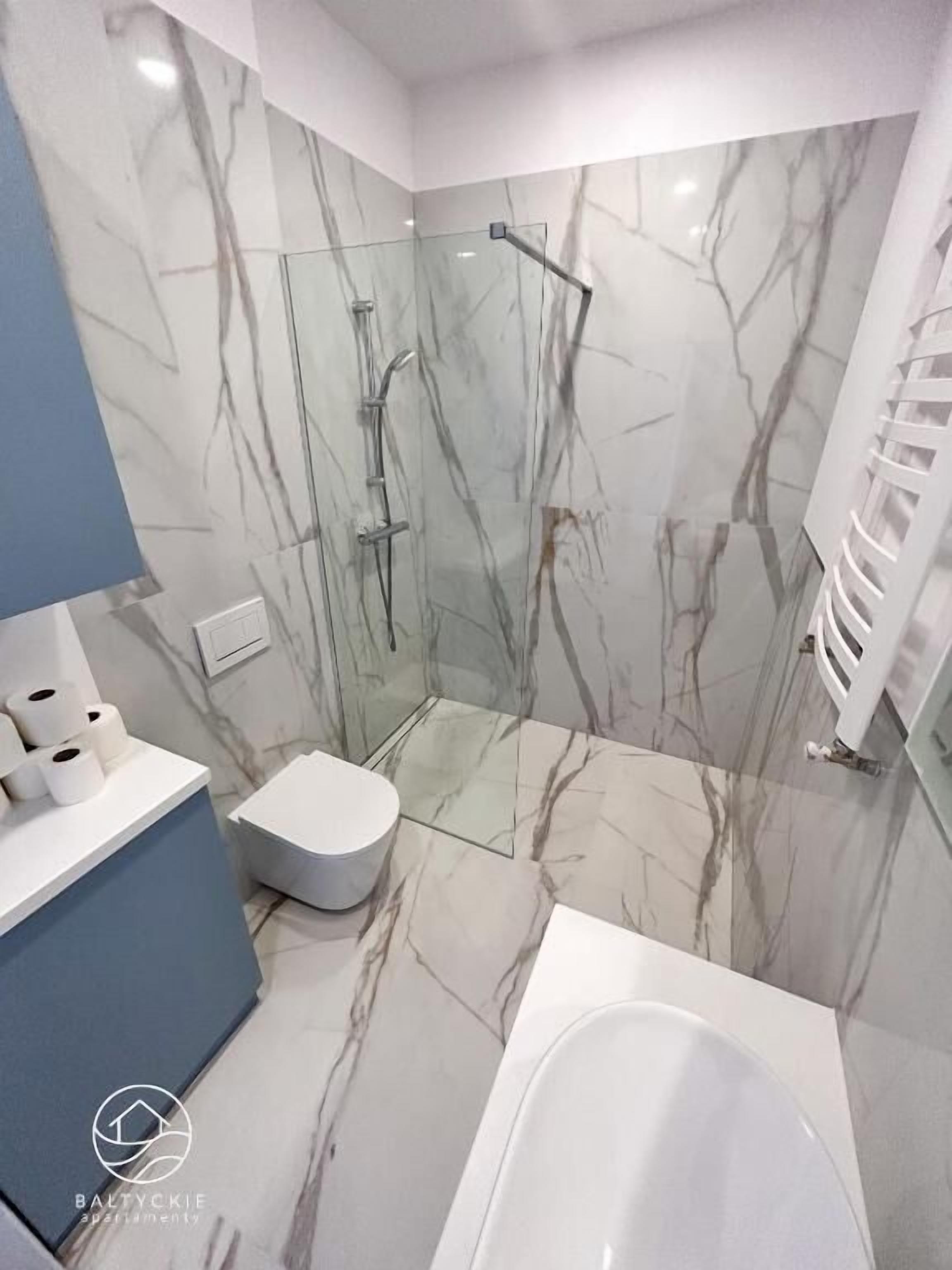 Een moderne badkamer met een douchecabine van glas, een wit toilet en een bad.