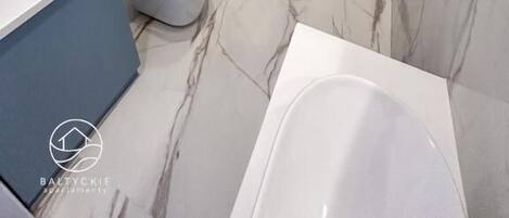 A modern bathroom with a glass-enclosed shower, a white toilet, and a bathtub.