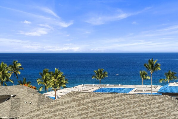 A resort with a pool area, palm trees, and a view of the ocean.