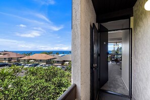 Habitación de hotel con vista al océano y coches estacionados.