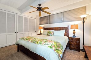 A bedroom with a bed, two nightstands, a ceiling fan, and a wardrobe.