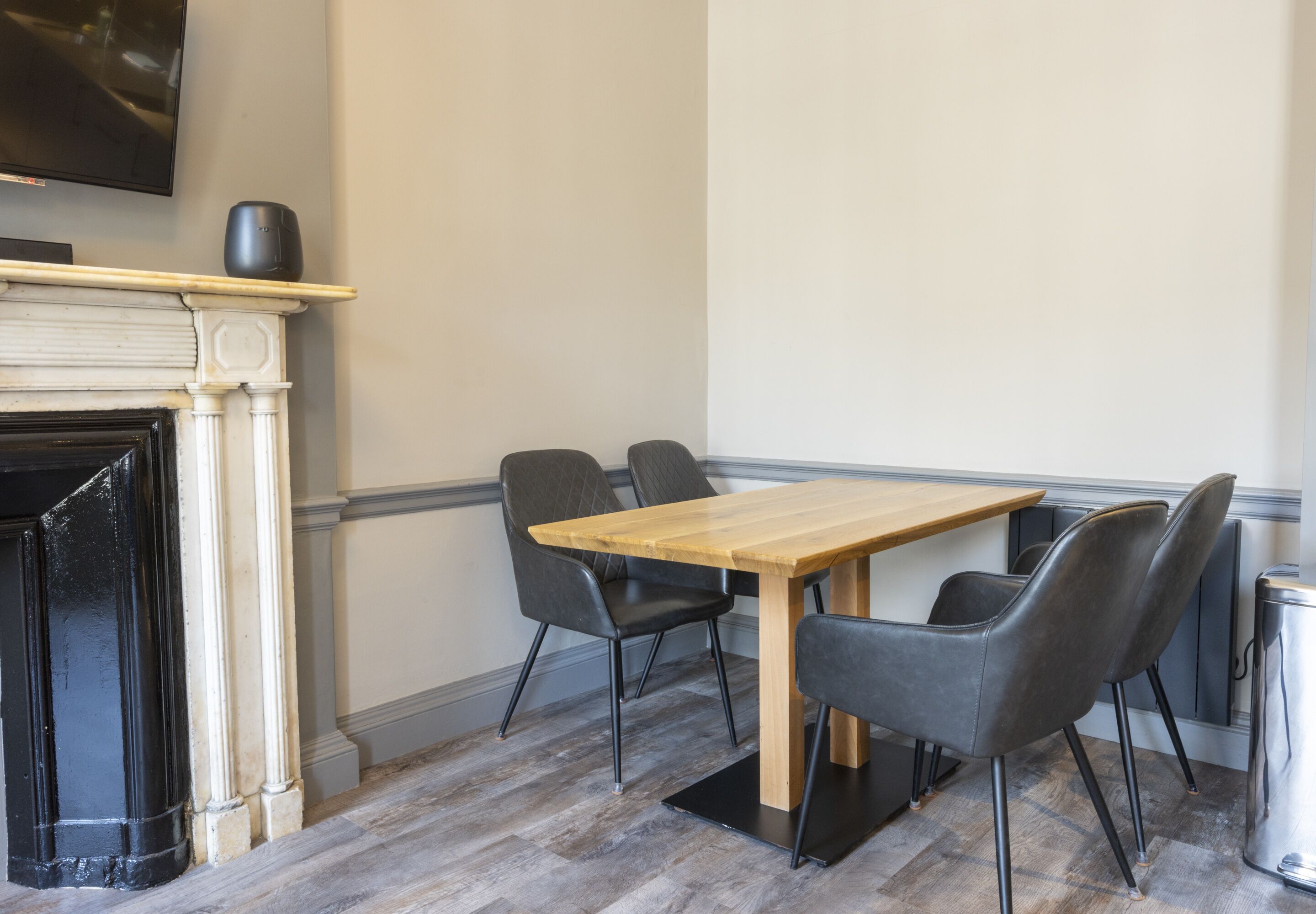 Un coin repas avec une table en bois et quatre chaises, une cheminée et un téléviseur fixé au mur.