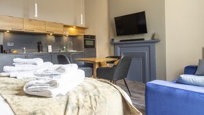 Une chambre d’hôtel moderne équipée d’un lit, d’une table à manger, d’un téléviseur fixé au mur et d’une cheminée.