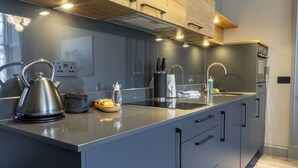 Une cuisine moderne dotée d’appareils électroménagers en acier inoxydable, d’un grand îlot central et de meubles de rangement en bois.