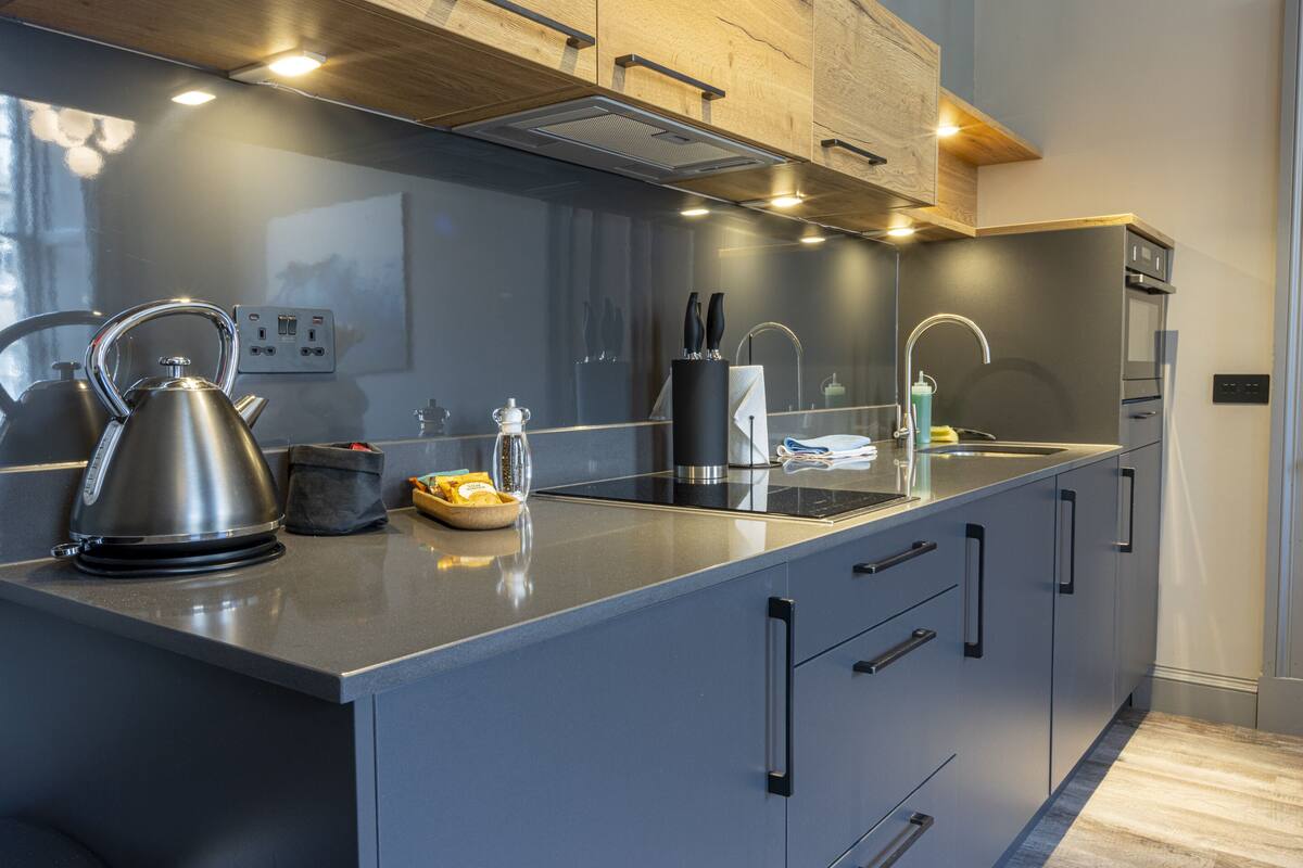 A modern kitchen with stainless steel appliances, a large island, and wooden cabinetry.