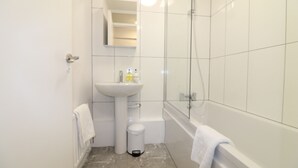 Une salle de bain moderne avec un lavabo blanc, une douche en verre et une baignoire.