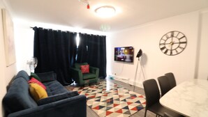 Un salon moderne avec un canapé, une table à manger et un téléviseur fixé au mur.