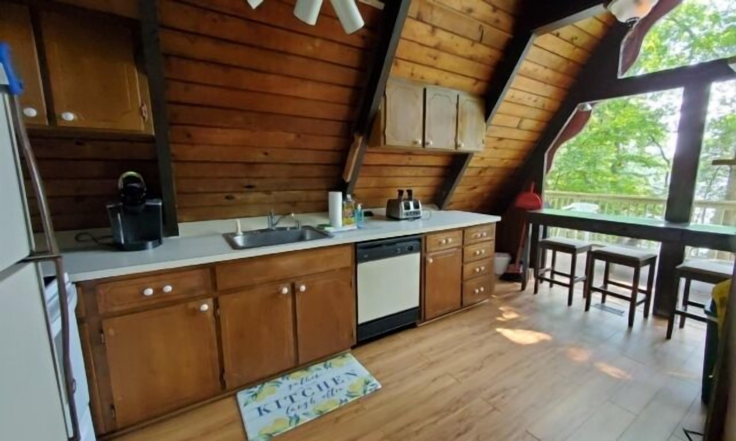 Una cocina con armarios de madera, un lavamanos y una zona de comedor con una mesa y sillas.