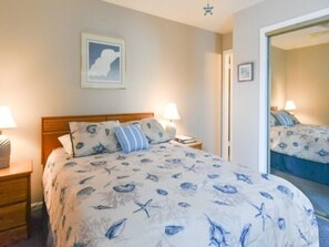 Een slaapkamer met een bed, twee nachtkastjes, een spiegel en een aan de muur hangend schilderij.