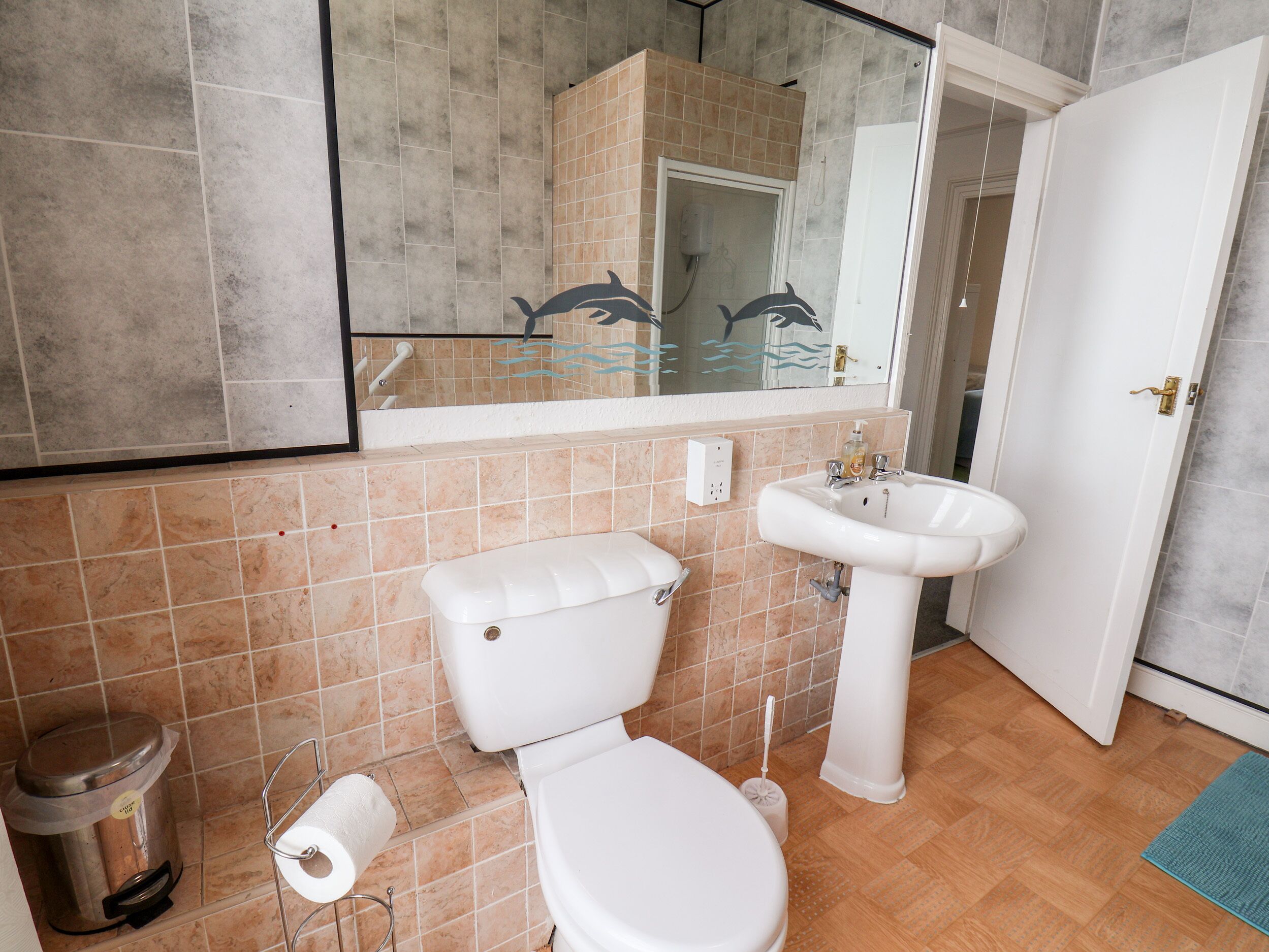A bathroom with a toilet, sink, and mirror.