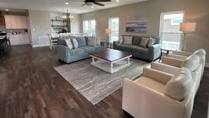 Uma sala de estar espaçosa com um sofá grande, uma mesa de centro e um espaço de jantar com um candelabro.