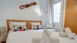 Een opgemaakt bed met kleurrijke kussens, een houten hoofdbord en een decoratie aan de muur.