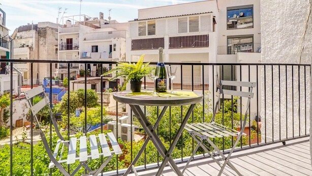 Een balkon met een tafel, stoelen en een bloempot.