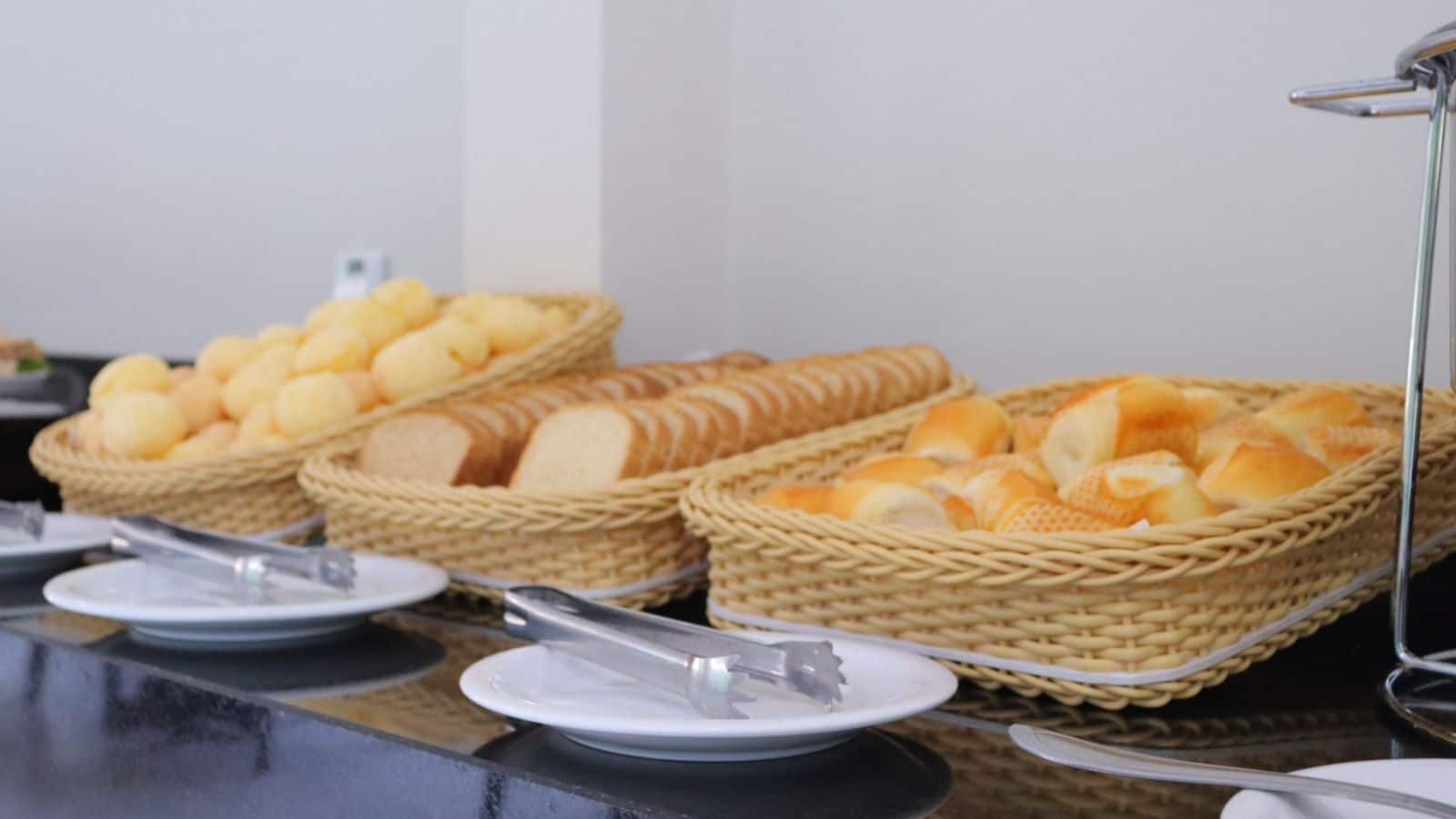 A buffet table with baskets of bread and rolls.