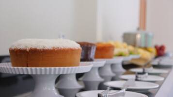Uma mesa de buffet com diversos produtos de pastelaria e uma apresentação de frutas.