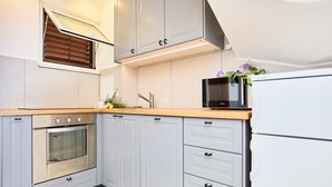 Eine moderne Küche mit grauen Schränken, einem Einbauofen, einer Mikrowelle und einem Kühlschrank.
