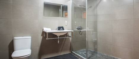 A modern bathroom with a toilet, a sink with a towel, and a glass-enclosed shower.