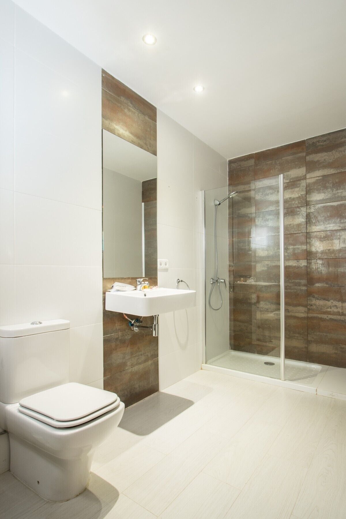 Een moderne badkamer met toilet, wastafel en douchecabine.