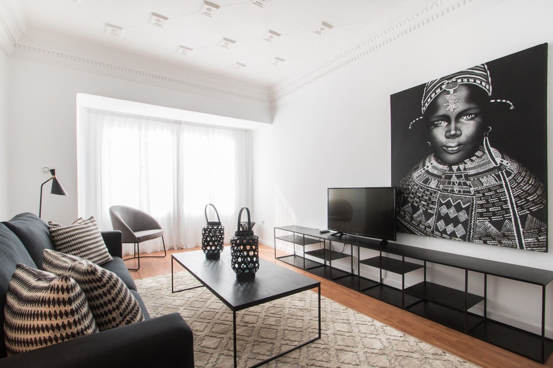 Un salon moderne avec un canapé, une table basse, un téléviseur et une grande œuvre d’art en noir et blanc accrochée au mur.