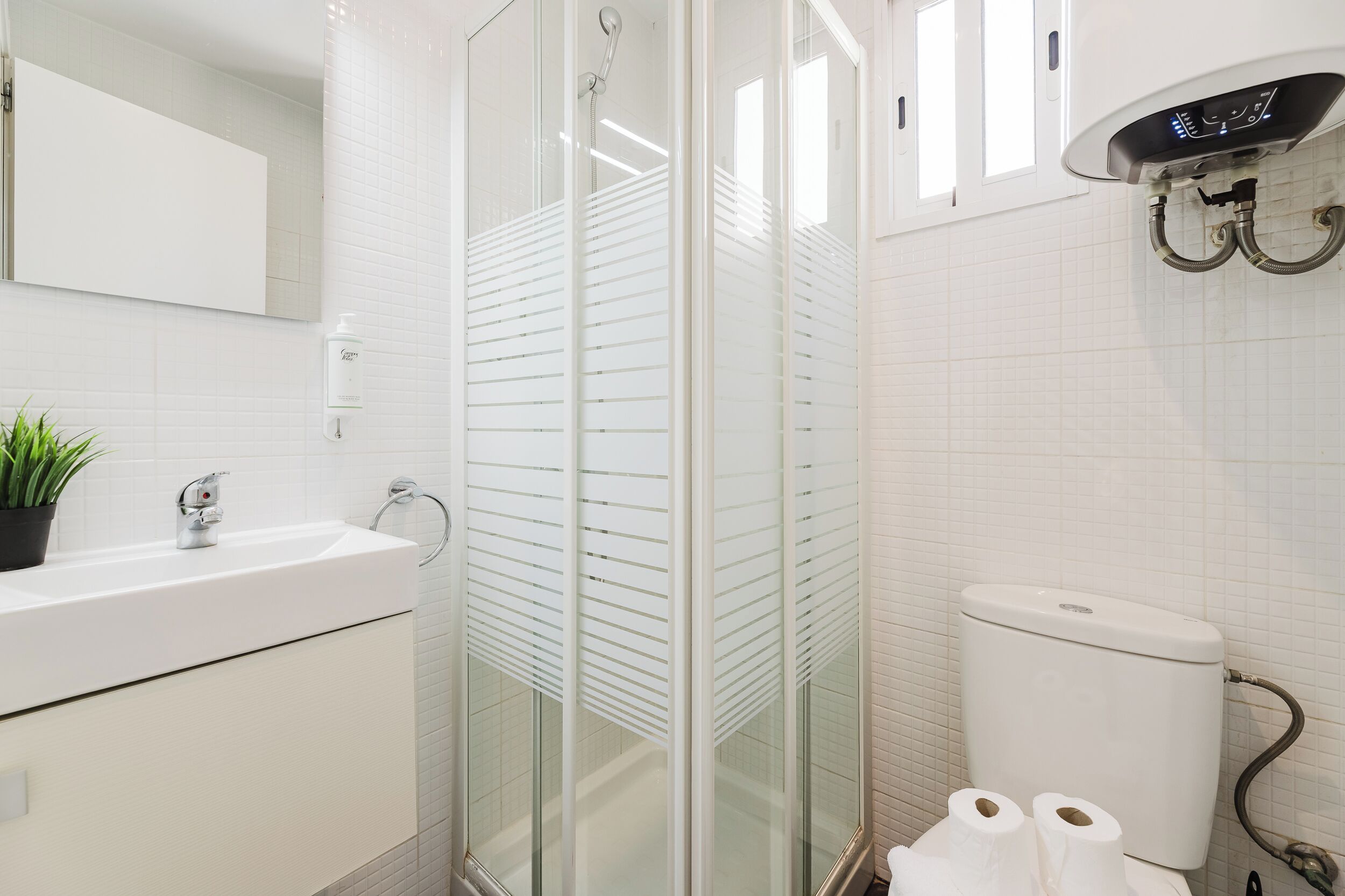 Een moderne badkamer met een douchecabine van glas, een witte wastafel en een toilet.