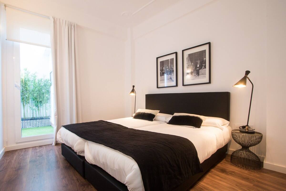 Een slaapkamer met een groot bed, twee bedlampjes en twee ingekaderde foto’s aan de muur.
