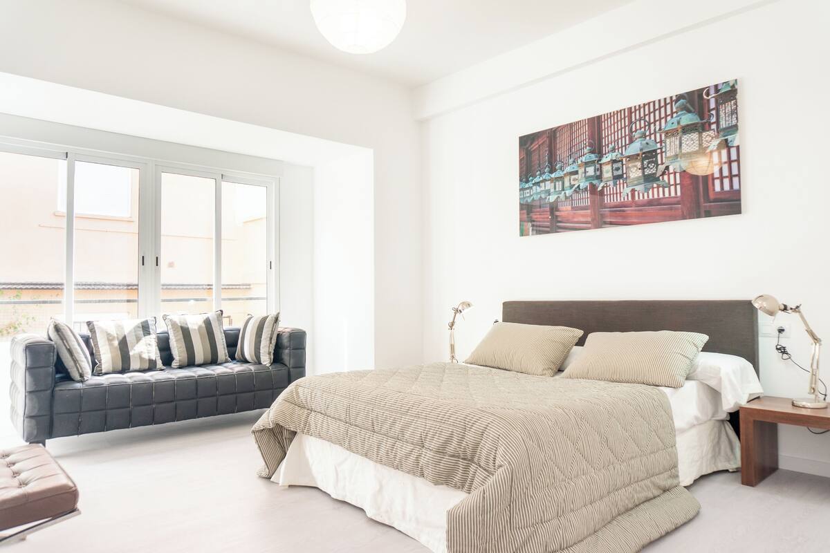 Een slaapkamer met een groot bed, een bank en een raam met uitzicht.