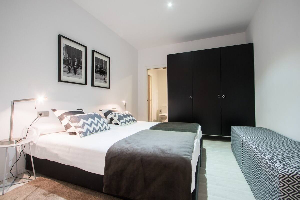 Een moderne slaapkamer met een bed, nachtkastjes, een kledingkast en twee ingelijste foto's aan de muur.