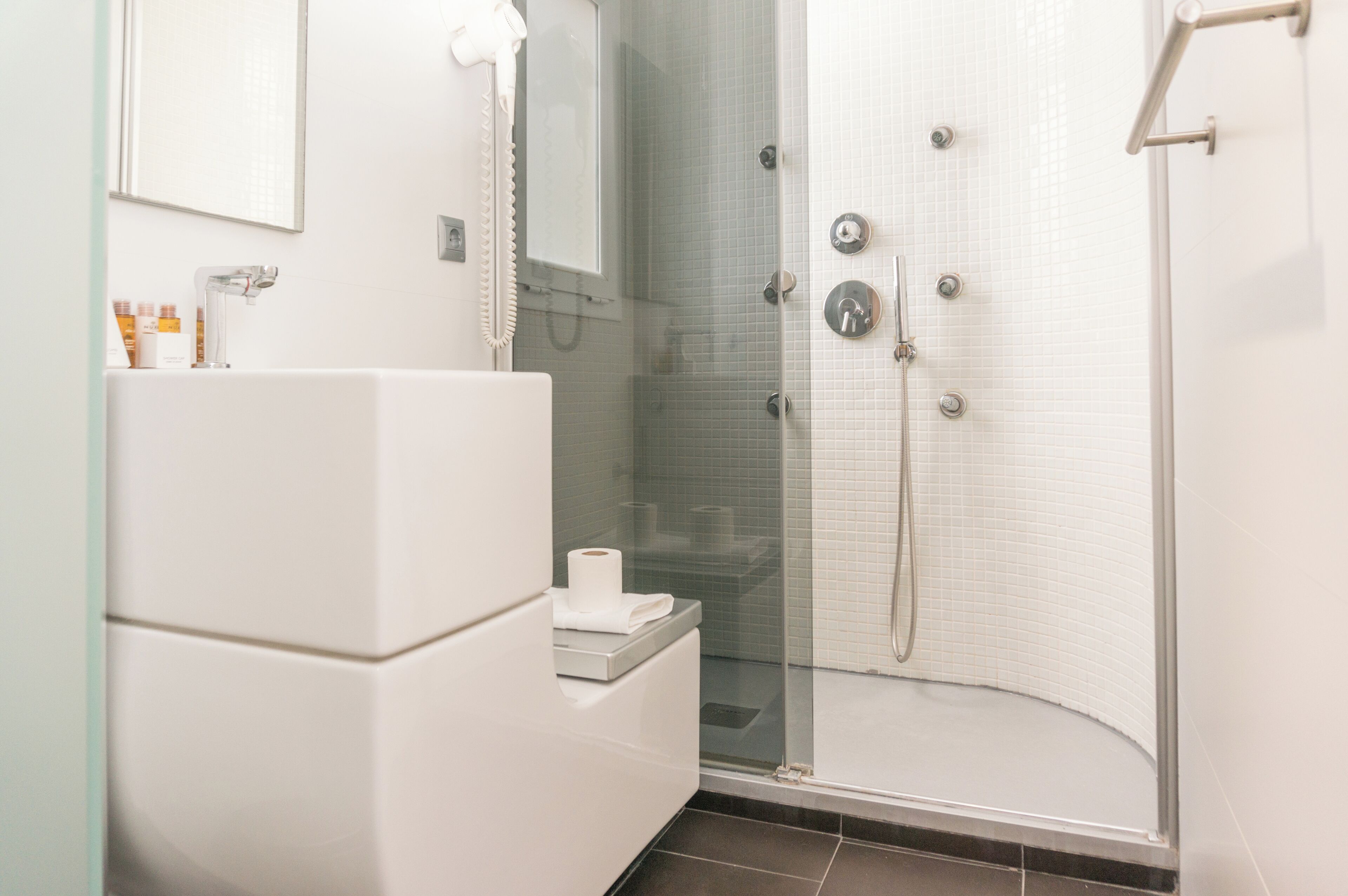 A modern bathroom with a glass-enclosed shower, a white sink, and a mirror above the sink.