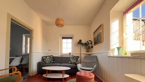 A living room with a sofa, armchair, ottoman, and a round table. - Cozy holiday apartment on a former farm in a quiet, green location (Hohnstein)